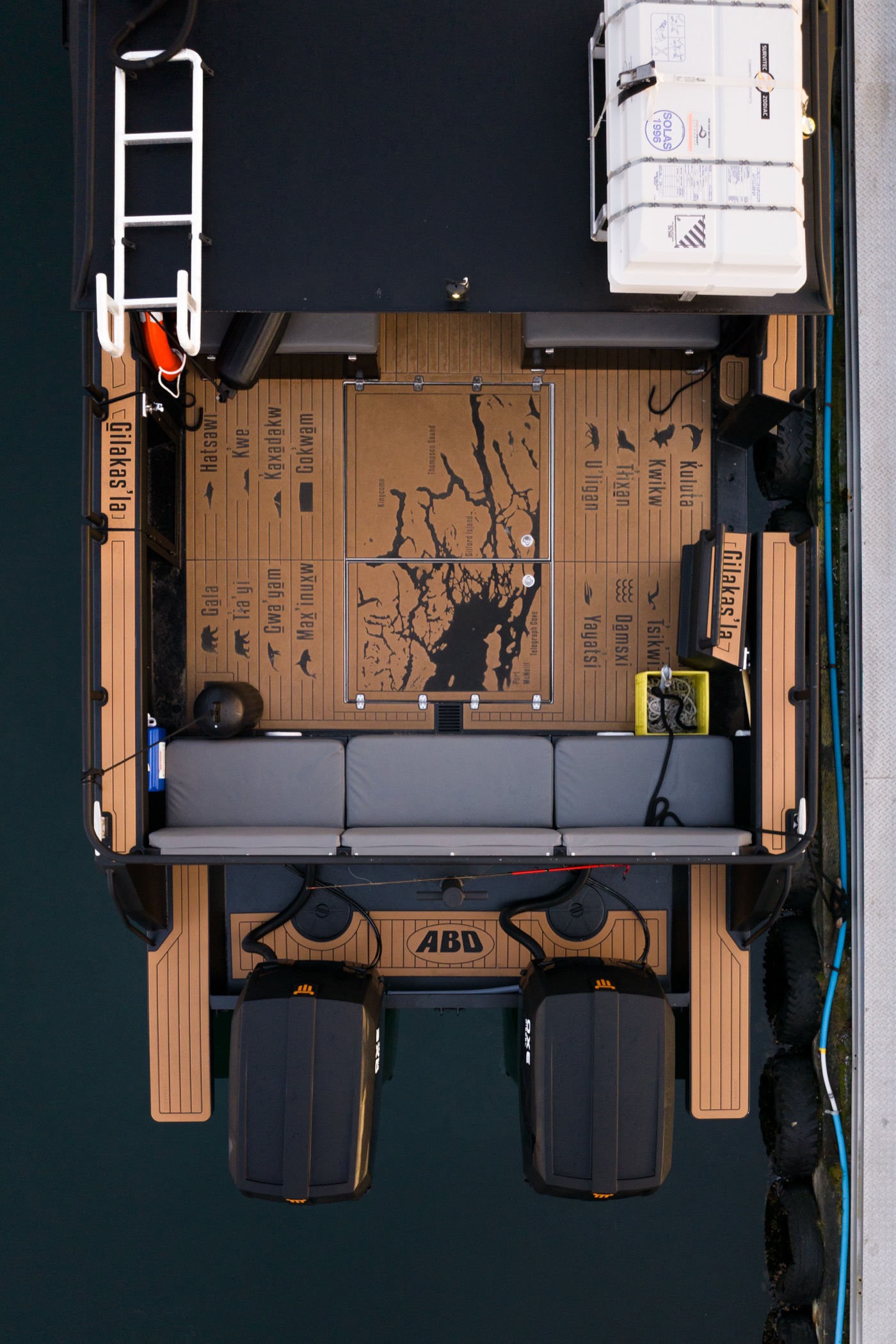 Overhead aerial view of Sea Wolf vessel deck featuring an Indigenous map with Kwak'wala place names and wildlife silhouettes, Kwakwaka'wakw cultural tour BC