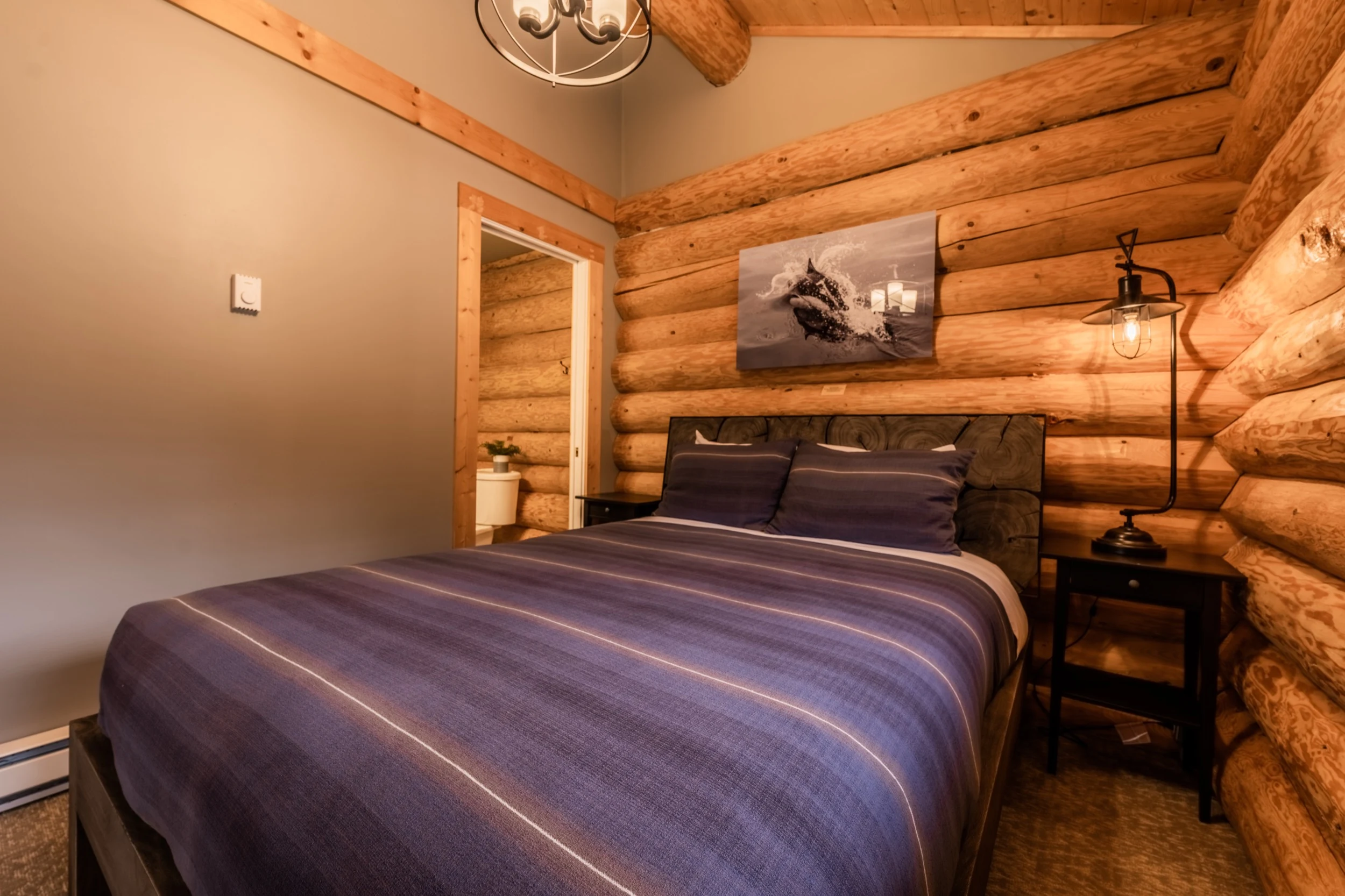 Cabin bedroom with queen bed and whale artwork at Sea Wolf Lodge